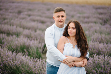 Man and woman standing and enjoys floral glade, summer nature. Loving couple walking at sunset. Family hugging in violet lavender field of flowers. France, Provence. Honeymoon trip, traveling. Closeup