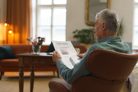Senior man reading newspaper in his apartment.