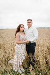 Man and woman embrace in nature. Loving couple hugs, walks, and enjoys glade and summer nature. Family hugging in wheat field. Honeymoon trip. Weekend vacation holidays concept. Love story.