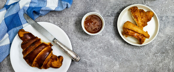 Fresh sweet croissants with orange jam for breakfast. Continental breakfast on a gray concrete table. Top view. Flat lay