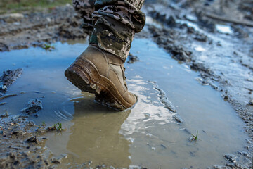Armed Forces of Ukraine. Ukrainian soldier. Brown military boots on mud and puddle.