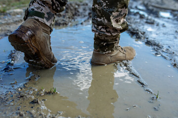 Obraz na płótnie Canvas Armed Forces of Ukraine. Ukrainian soldier. Brown military boots on mud and puddle.