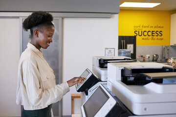 Young Black woman uses photocopier machine in shared office workspace