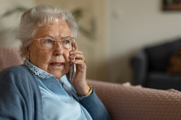 Portrait of senior woman sitting at home and calling.
