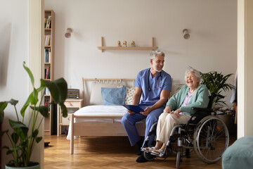 Caregiver doing regular check-up of senior woman in her home. - obrazy, fototapety, plakaty