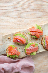 Toasts with avocado and smoked salmon on the wooden board