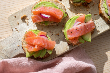 Toasts with avocado and smoked salmon on the wooden board