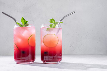 Delicious blueberry lime lemonade with soda water and blueberries on grey table. Fresh summer cocktail