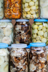 Pickled mushrooms (chanterelles, milk mushrooms, porcini mushrooms) in jars on the counter. Small home business. Own production.