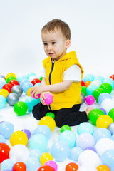 Fototapeta na wymiar Playful boy having fun in playground. Little kid playing with colorful balls.