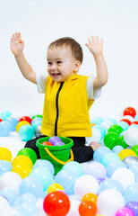 Fototapeta na wymiar Little kid playing with colorful balls. Playful boy having fun in playground.