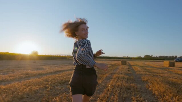 Stabilized commercial hand held shot of happy emotional woman run free in field during sunset. Emotions and feelings of happiness and freedom in nature. Travel wanderlust. Young woman run free
