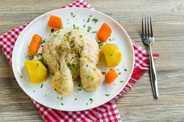 Boiled chicken legs and vegetables designed on a white plate with buttered rice.Turkish cuisine