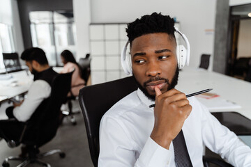 Young african american man using headphones while working at office
