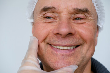 mature male face, man 60-65 years old years old, doctor, beautician, cosmetologist examines...