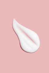 A dab of cosmetic cream. Light, smooth surface. Texture of spreadable cream. Liquid cream smear. On a pink background.
