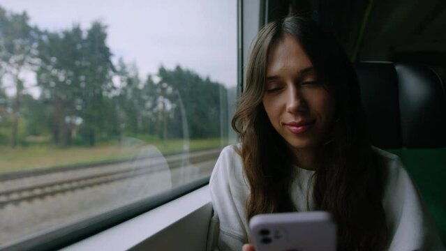 A young woman listens to music from her phone while traveling by train. Brunette enjoys the trip