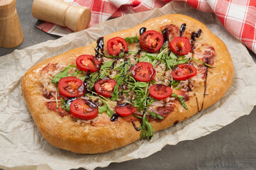 pizza with cheese and ham tomatoes and arugula