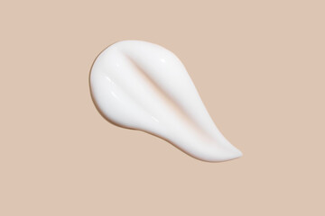The flowing cream on a beige background. Smudged flowing smear of cosmetic cream.