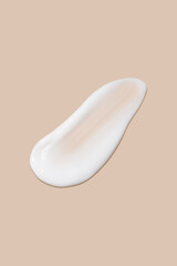The flowing cream on a beige background. Smudged flowing smear of cosmetic cream.