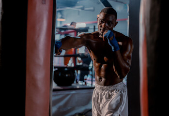Fototapeta na wymiar Boxers at the professional level routinely train by punching and kicking sandbags. To be successful in the individual's career, self-discipline, determination, and patience are essential qualities.