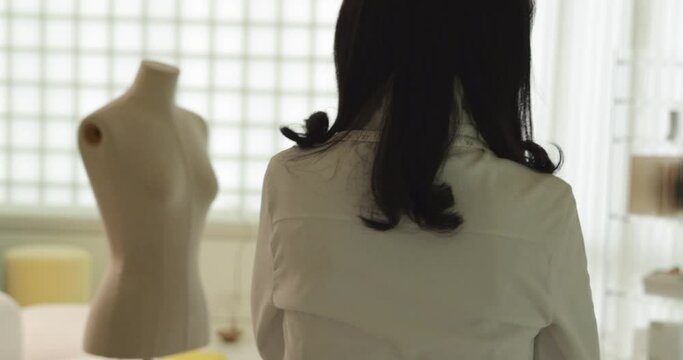 줄자를 목에 두르고 걸어가는 흰색 블라우스를 입은 여성 디자이너