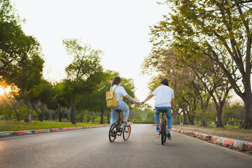 Obraz premium spring is comming concept with happy and cheerful feeling of asian couple riding bicycle together