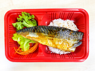 Saba fish grilled with salad in the food container on the table