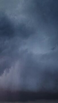 Lot of lightning during a thunderstorm. Storm clouds are moving fast on the viewer, timelapse. Vertical video
