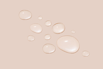 Drops of transparent gel or water in different sizes. On a beige background.