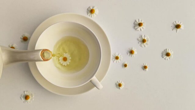 A cup of chamomile tea on a white background with flower buds inside. Soothing and healing natural herbal infusion. Flat lay, top view. Herbal remedy for insomnia. Concept lifestyle. Super-food.
