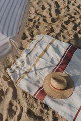 Obraz na płótnie Canvas Straw hat, umbrella, beach towel on beach sand. Minimal feminine fashion vogue background