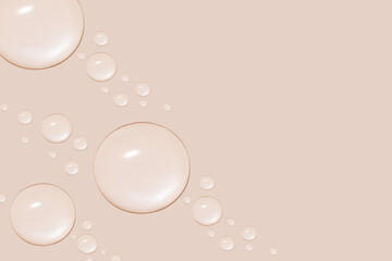 Drops of transparent gel or water in different sizes. On a beige background.