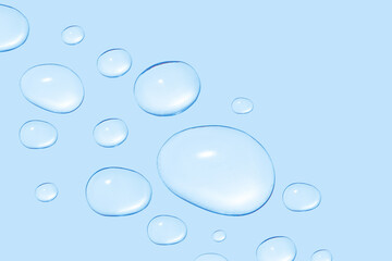 Drops of transparent gel or water in different sizes. On a blue background.