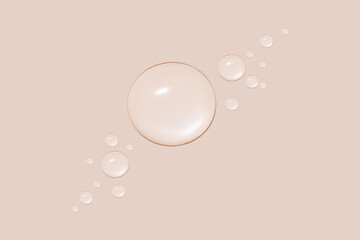 Drops of transparent gel or water in different sizes. On a beige background.