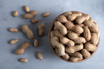 Bowl full of shelled and roasted peeled peanuts on light blue background,top view
