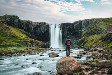 Gufufoss waterfall flowing with asian tourist woman standing on the rock at Seydisfjordur, East of...