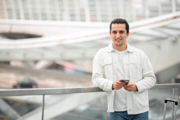 Tourist Man Using Cellphone Sending Messages Standing At Modern Airport