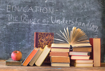 Stack of hardback books with slogan in front of a blackboard.Learning,education,reading,back to school concept. - obrazy, fototapety, plakaty