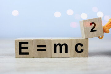 The Albert Einstein physics equation is E equals m c squared in a wooden block of dice. physics education concept