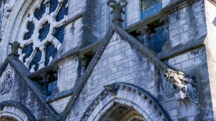 Fototapeta na wymiar Fragment of the facade wall of Saint Fin Barre's Cathedral. Detail of the facade of the Catholic Church in Cork, Ireland. Neo-Gothic building