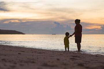 Fototapeta na wymiar parent and child walk on the beach at sunset