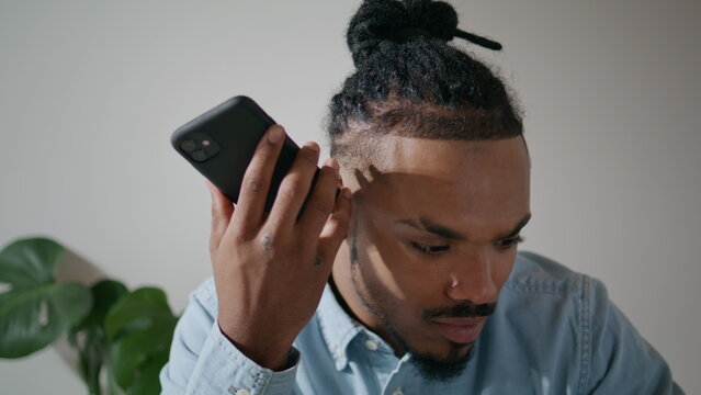 Dreadlocks guy listening message at loft office closeup. Man holding smartphone - Powered by Adobe