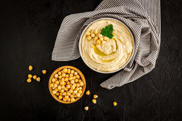 Bowl of chickpeas hummus with oil and herbs, top view