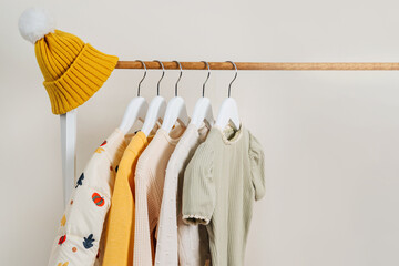 Clothing Rack with children's outfits close up. Fashion clothes in autumn colors and hat on hangers in wardrobe. Kids wardrobe. Set of kids clothes and accessories.