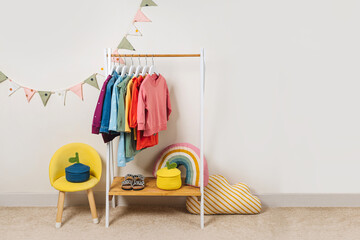 Clothing Rack with kids outfits and storage baskets in children's room. Fashion clothes in  rainbow...