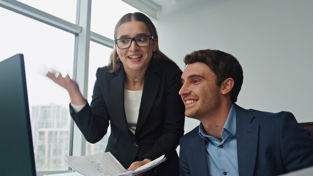 Happy businesswoman talking colleague. Two smiling partners working computer