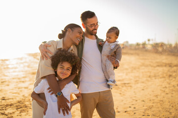 Seaside serenity. Young multiracial parents and kids walking by seaside and enjoying family bonding time outdoors