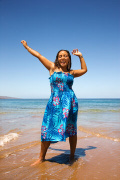 Yound-adult Black woman standing in shore with arms stretched.