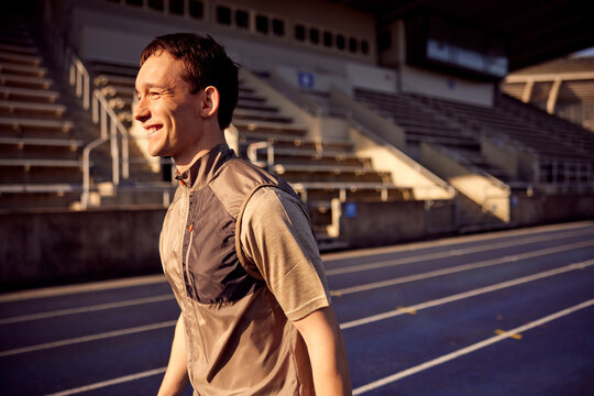 Smiling young man standing on an outdoor running track
